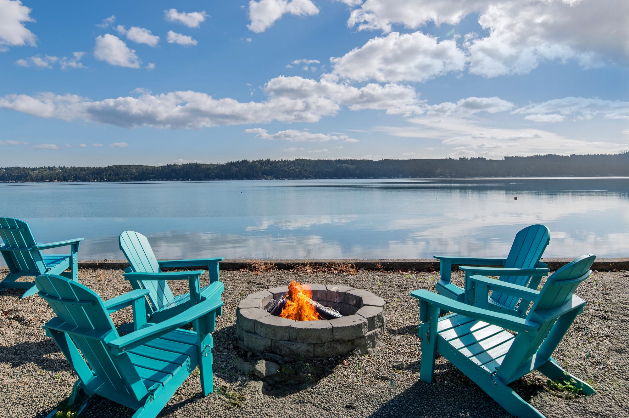 The Horizon: fenced beach with blue Adirondack chairs and firepit on Hood Canal